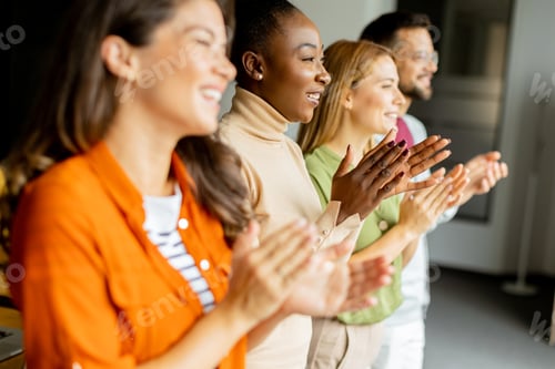 Preview: Young multiethnic startup team standing and applauding in the modern office