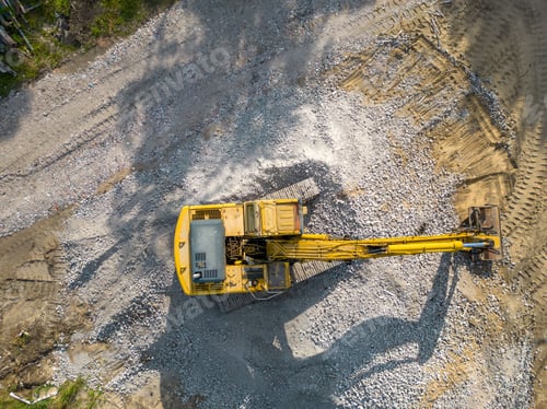 Preview: Aerial view of a yellow metallic crane working atop a pile of grey gravel