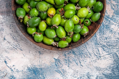 Preview: Half shot of delicious natural fresh feijoas in a brown pot on the left side of ice table