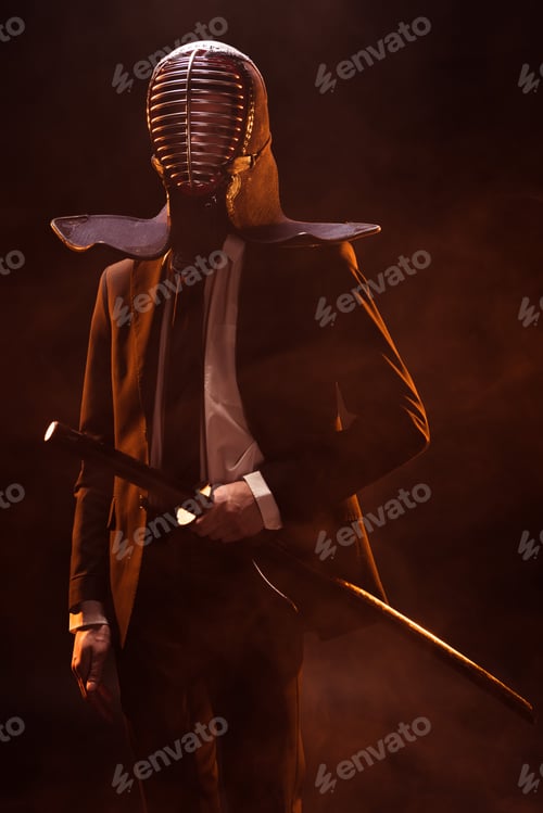 Preview: Man in formal wear and kendo helmet holding bamboo sword on dark
