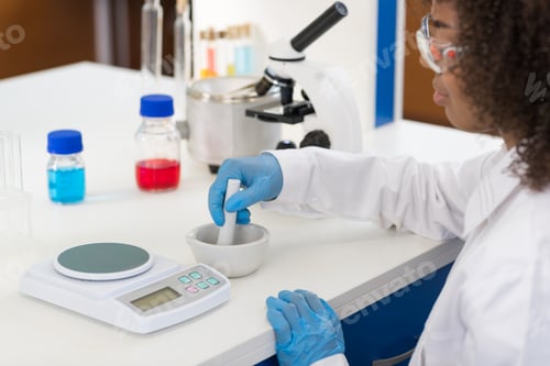 Preview: Female Scientist Using Mortar Working In Laboratory Making Chemicals Powder For Experiment