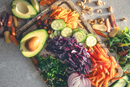 Preview: Sliced fresh vegetables on a cutting board on the kitchen table, top view.