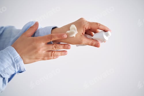 Preview: Hands in a blue shirt hold a tube of cream.