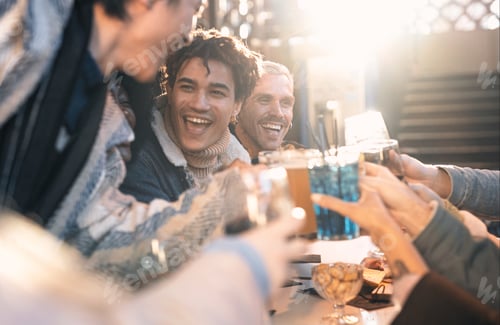 Preview: A group of grinning friends gather around a bar table, raising their frosty beer glasses