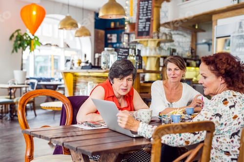 Preview: Businesswomen looking at laptop during lunch in restaurant
