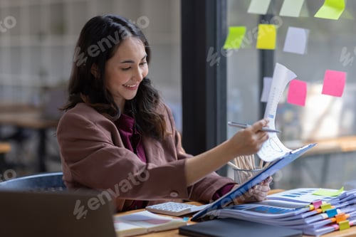 Preview: Freelancer Happy business Asian woman in knitwear taking notes at laptop sitting at desk office,
