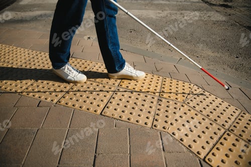 Preview: young blind man with white cane walking across the street in city