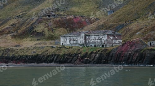 Preview: Abandoned building along the coastline of Grumant in Svalbard surrounded by rugged terrain