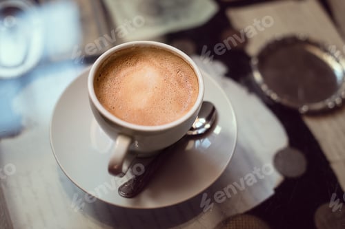 Preview: A cup of coffee on the table covered with old letters and vintage coins.