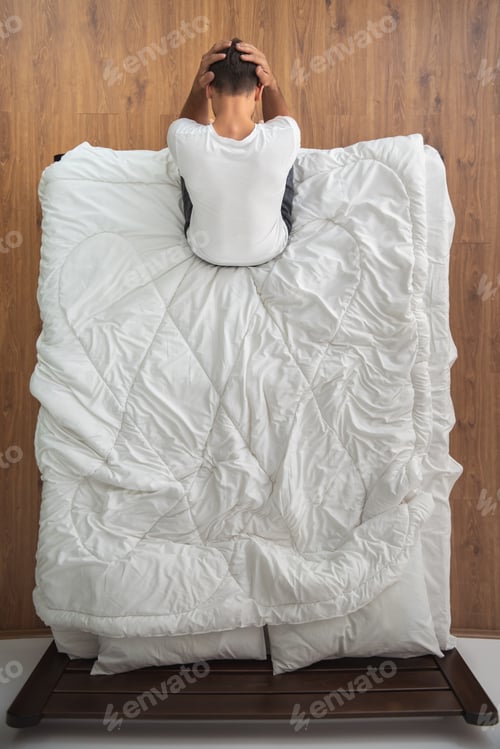 Preview: The depressed man sitting on the bed. view from above