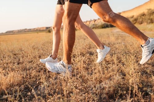 Preview: Cropped image of a young couple legs in sneakers running