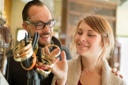 Preview: Two people, a man and woman looking at jewellery displayed on a mannequin hand.