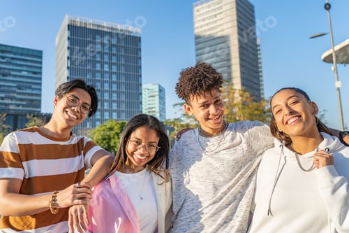 Preview: Multiethnic cheerful teenagers laughing and hugging lovingly in the street looking to the camera.