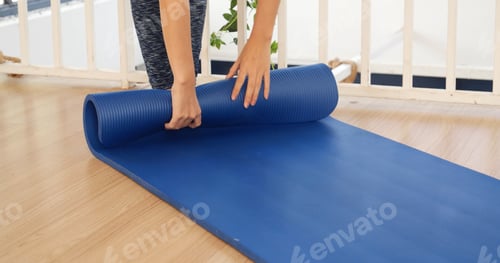 Preview: Banner Woman hands rolled up yoga mat on gym floor in yoga fitness training room.