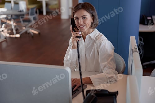 Preview: Smiling european woman worker talk phone with client sit on her workplace in office