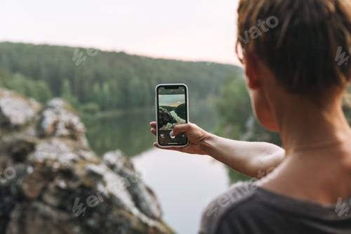 Preview: Young woman traveller with backpack take photo of beautiful view of mountains and river
