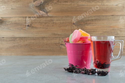 Preview: Colorful marmalade candies and glass of tea on marble table