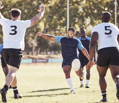 Preview: Mixed race rugby player attempting a dropkick during a rugby match outside on the field. Hispanic m