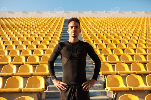 Preview: Handsome African American sportsman confidently looking in camera among empty stadium seats