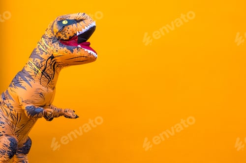 Preview: one big and tall dinosaur enjoying and having fun with orange background - copy and blank space