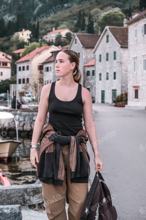 Preview: Young woman exploring a quaint European coastal town, embodying the digital nomad lifestyle and the