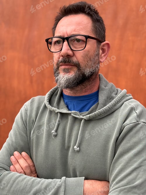Preview: Portrait of pensive and worried adult man with beard and glasses. Crossed arms posture