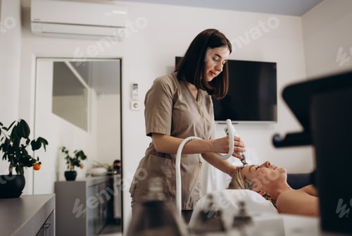 Preview: Beautician makes a young beautiful girl a vacuum facial treatment for rejuvenation. Girl is undergoi