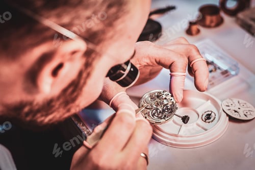 Preview: Mature clockmaster is fixing old watch for a customer at his busy repairing workshop