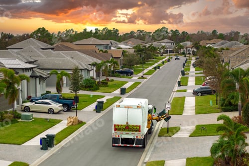 Preview: Automated modern garbage collector truck loading waste on Florida town street.