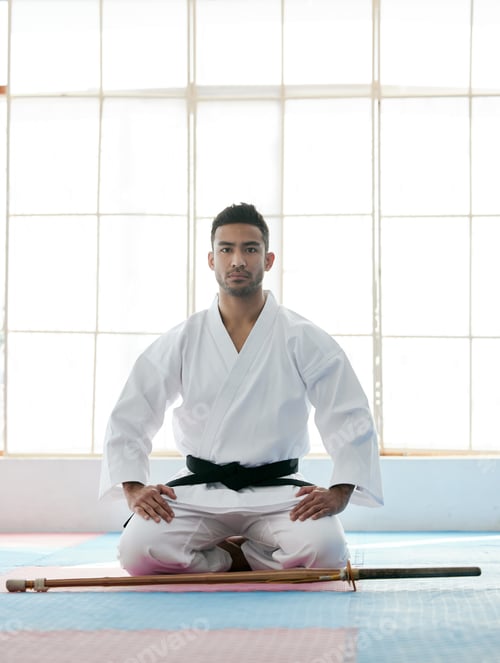 Preview: Full length portrait of a handsome young martial artist practicing bojutsu in his dojo