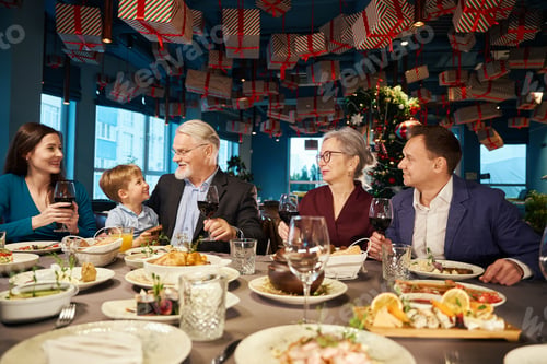 Preview: Satisfied family enjoying Christmas dinner together in cozy restaurant