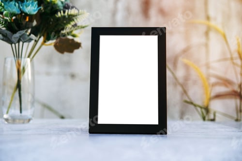 Preview: Blank white picture frame and artificial flowers in a glass on a cement table