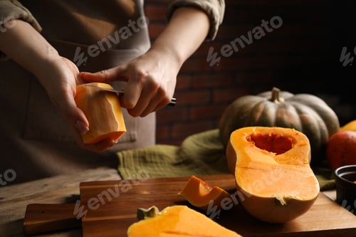 Preview: Woman peeling pumpkin at wooden table, closeup