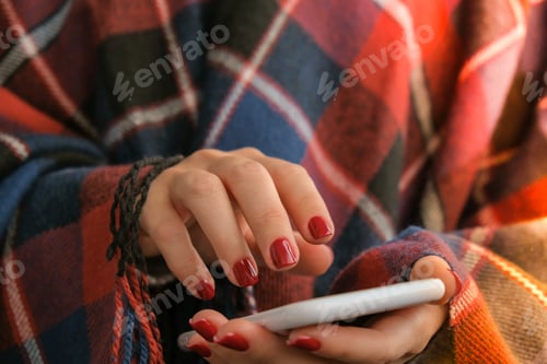Preview: Cozy Woman Holding Phone Wearing Plaid Blanket