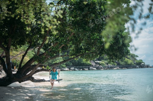 Preview: A Young Woman Is Swinging On A Swing In The Shade Of A Big Tree By The Sea. Girl On The Beach Swing