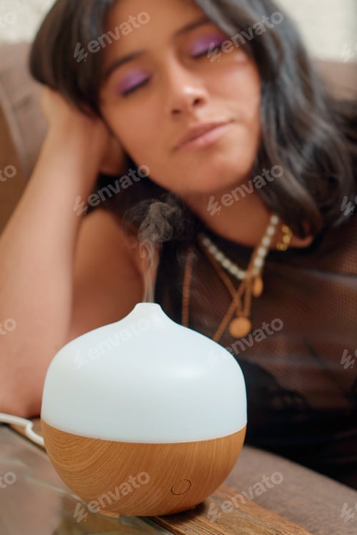 Preview: Young latina woman using aromatherapy to relax. Wellness concept.