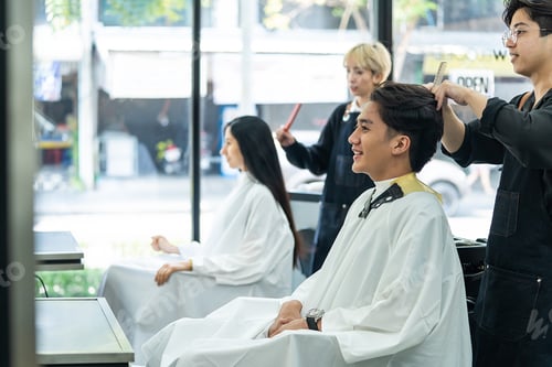 Preview: Professional young Asian female hairdresser or hair stylist cut woman customer's hair in salon