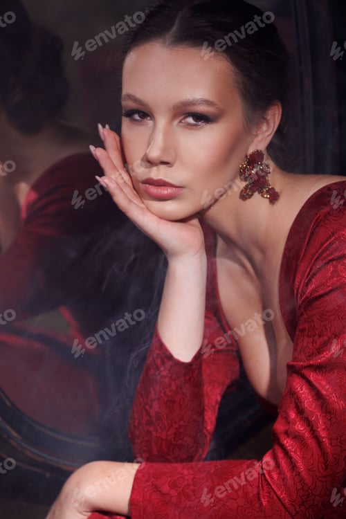 Preview: Beautiful young girl in red dress in retro style in front of mirror. Fashion photoshoot