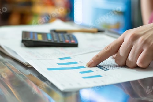 Preview: a latina girl's hand is pointing to the sales statistics bars. in the background a pencil