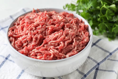 Preview: Raw ground meat in bowl and parsley on table, closeup