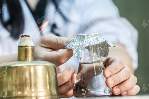 Preview: Closeup of a person putting foil on a glass test tube in a laboratory