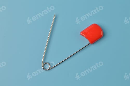 Preview: Red safety pin isolated on a blue background