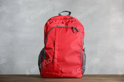 Preview: Red backpack on wooden table against gray background