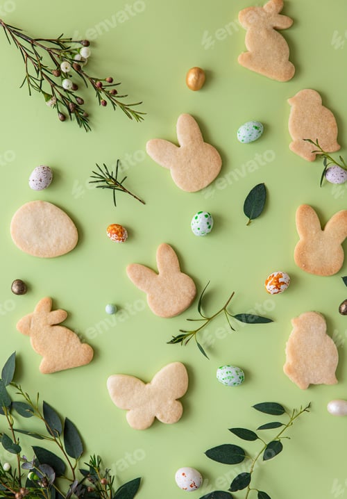 Preview: Easter cookies, candies shaped eggs, eucalyptus, flowers and quail eggs on green pastel background.