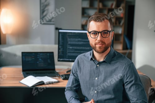 Preview: Software developer is sitting and posing. Man in formal clothes is working in the modern office