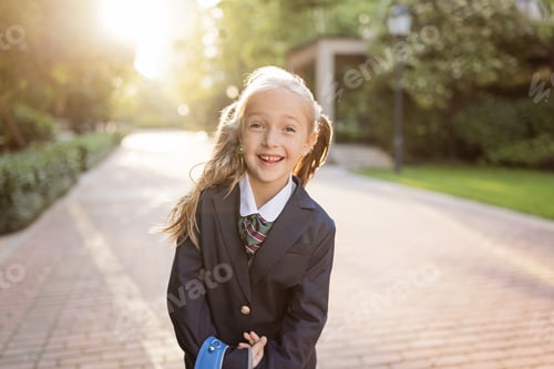 Preview: Schoolgirl back to school after vacations. Pupil in uniform and backpack early morning outdoor