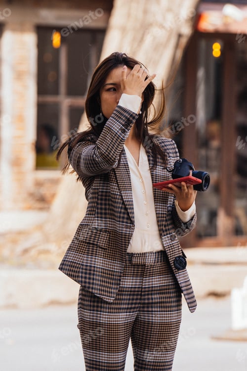 Preview: Woman in gray plaid suit holding a phone standing outdoor