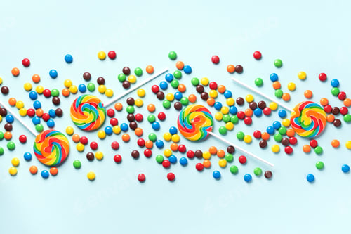 Preview: Multicolored lollipop, rainbow colorful candies on blue background. Coated chocolate sweet pieces