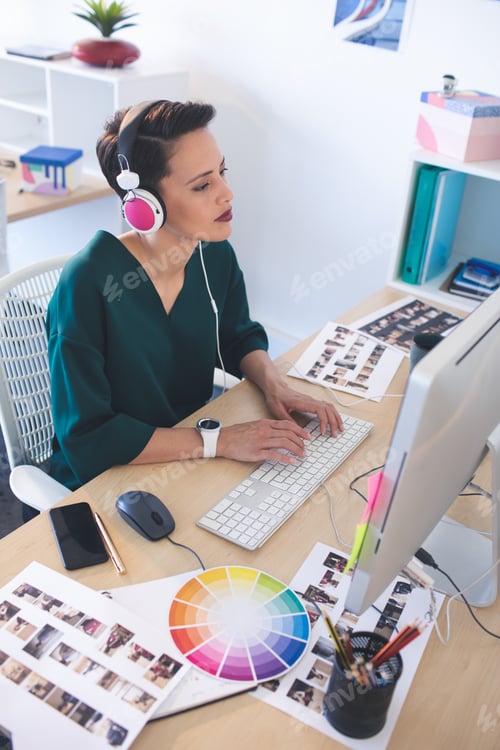 Preview: Beautiful female graphic designer working on computer at desk in the office