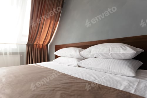 Preview: Cozy bedroom with neatly arranged pillows and natural light streaming through the window